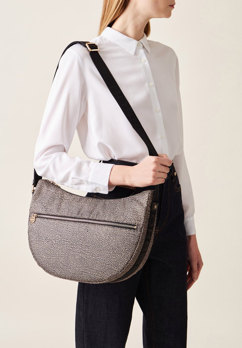 Hobo bag with a textured black and white pattern, featuring a top zip closure and an adjustable strap. Smooth black accents near the zipper.