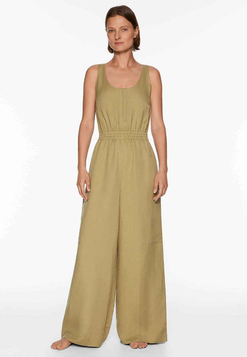 Olivgrüner Jumpsuit mit einer lockeren Passform, weitem Rundhalsausschnitt, elastischem Bund und weitem Bein. Hergestellt aus strukturiertem Stoff, mit seitlichen Taschen.