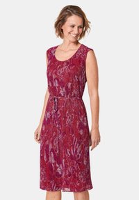 Rotes floral gemustertes Kleid mit ärmellosem Design, tailliertem Schnitt und knielangem Saum. Das Material wirkt leicht und strukturiert.