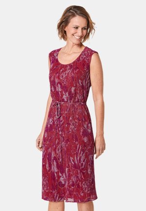 Rode jurk met bloemenpatroon, zonder mouwen, met een getailleerde taille en een rok tot de knie. Het materiaal lijkt licht en gestructureerd.