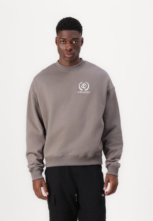 Gray sweatshirt featuring a crew neckline, ribbed cuffs, and a logo on the left chest. Fabric appears soft and textured.