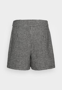 Kratší kalhoty s černobílým vzorem houndstooth, s plochým pasem a sklady vpředu. Tkanina vypadá texturovaně a má strukturovaný tvar.