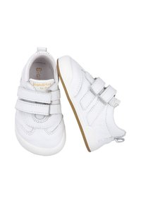 Zapatillas infantiles blancas de cuero sintético, con dos correas ajustables de velcro, puntera redondeada y suela de goma color marrón.
