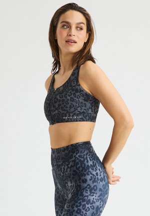 Sportbeha en legging set in donkergrijs met een zwart luipaardprint. Heeft een rits aan de voorkant, brede bandjes en een soepele, rekbare stof.
