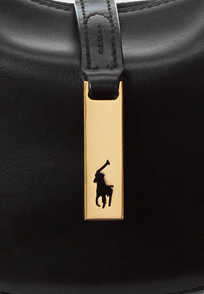 Μαύρη δερμάτινη τσάντα χειρός με χρυσό ορθογώνιο ταμπελάκι που φέρει το λογότυπο μαύρου παίκτη πόλο. Λείο υλικό με δομημένο σχήμα.