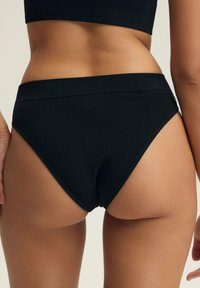 Czarne, żeberkowane majtki o wysokim stanie z gładkim pasem, charakteryzujące się bezszwowym wzornictwem i miękką teksturą dla komfortu.