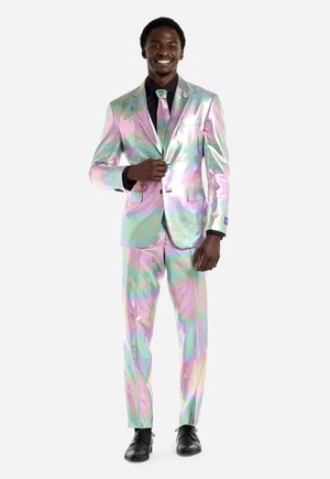 Iridescent Anzug aus mehrfarbigem Stoff in den Farbtönen Pink, Grün und Blau, mit taillierter Passform und passender Krawatte, kombiniert mit schwarzen Schuhen.