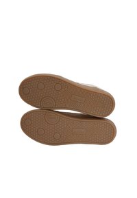 Scarpe con suola in gomma caratterizzate da un motivo a nido d'ape. La suola presenta forme arrotondate e esagonali. Il materiale superiore beige è visibile sui bordi.