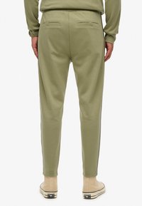Licht olijfgroene joggingbroeken van een zachte katoenmix, met een taps toelopende pasvorm, achterzakken en zwarte zijstrepen.