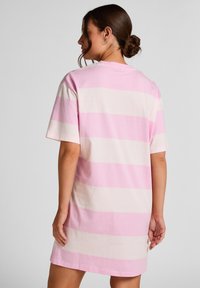 Ροζ και λευκό ριγέ υπερμεγέθυνσης φόρεμα T-shirt κατασκευασμένο από απαλό βαμβάκι, με κοντά μανίκια και στρογγυλή λαιμόκοψη, με μήκος μέχρι το γόνατο.