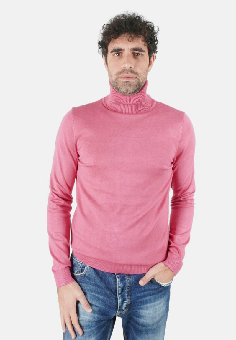 Maglione dolcevita rosa in morbido materiale a maglia, con maniche lunghe e dettagli a coste sul colletto e sull'orlo, abbinato a jeans di denim.