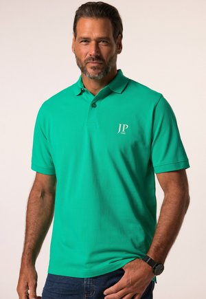 Grøn poloshirt lavet af tekstureret stof, med en krave, tre knapper og et lille "JP 1880" logo på venstre bryst.