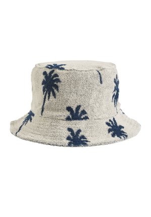 Καπέλο bucket φτιαγμένο από υφασμένο μπεζ ύφασμα, με ναυτική μπλε σχέδια φοίνικα. Στρογγυλή κορυφή, φαρδύ γείσο και χαλαρός σχεδιασμός.