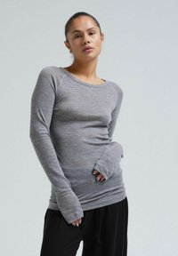 Gray long-sleeve top in a soft, textured fabric, featuring a rounded neckline and fitted design with extended cuffs, paired with black pants.