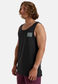 Canottiera nera in cotone, con un design a onde colorate sulla tasca del petto. Design semplice con vestibilità rilassata e scollature ampie.