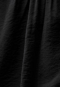 Tissu noir avec des plis visibles et des plis verticaux créant des ombres texturées.