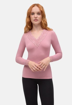 Top de manga larga rosa con escote en V y detalle de encaje. La tela es suave y ajustada, en contraste con leggings negros.