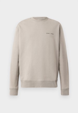 Beige genser med rund hals, ribbede mansjetter og nederkant. Viser "SAMSØE SAMSØE"-logoen i mørk trykk på brystet. Glatt bomullsmateriale.