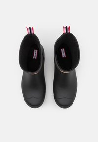 Schwarze Gummistiefel bis Knöchel mit glatter Oberfläche, weicher innenseite und roten und weißen gestreiften Schlaufen an der R�ückseite. Minimalistisches Design.