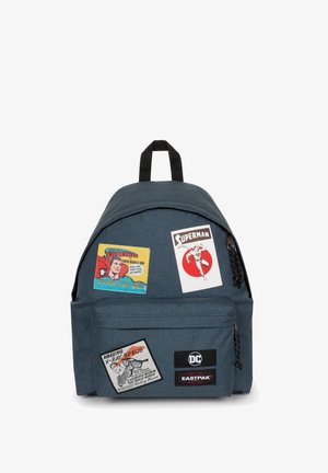Mochila de tela azul con múltiples parches de personajes de cómics, incluidos Superman y X-Ray Specs, y una etiqueta de marca negra en la parte inferior.