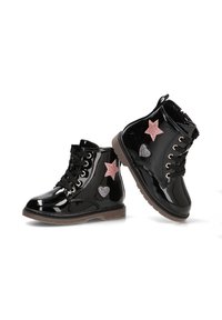 Botas de tobillo de charol negro con acabado brillante, diseño de cordones, acentos de estrella rosa y corazón plateado, y suelas de goma marrón.