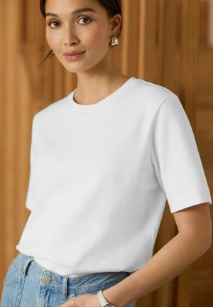 Witte katoenen T-shirt met een ronde halslijn en korte mouwen, gecombineerd met lichtblauwe denim, met een relaxte pasvorm en een zachte textuur.