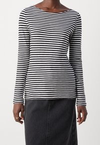 Schwarz-weißer gestreifter Langarmshirt mit weitem Ausschnitt und lockerem Schnitt, kombiniert mit einem dunklen Jeansrock. Glatte Textur.