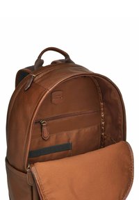 Zaino in pelle marrone con esterno testurizzato, spallacci imbottiti e molteplici tasche. Gli interni presentano una fodera in tessuto liscio e scomparti con cerniera.