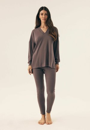 Grey loungewear set featuring a long-sleeve, V-neck top with dropped shoulders and ribbed texture, paired with fitted ribbed pants.