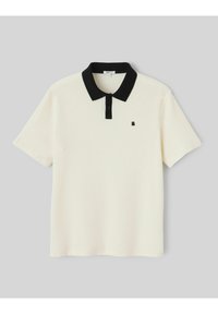 Polo blanc à manches courtes avec col noir, patte de boutonnage noire et petit logo noir sur la poitrine gauche.