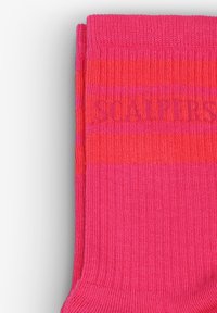 Calcetines de color rosa brillante con rayas horizontales y textura acanalada. Presentan el nombre de la marca "SCALPERS" en un tono de rosa ligeramente más oscuro. Diseño clásico.