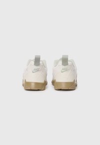 Un paio di sneakers Nike bianche e beige con linguette grigie, mostrato da dietro su uno sfondo bianco uniforme.