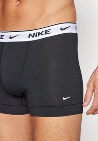 Schwarze Boxershorts mit einem weißen elastischen Bund, der das Nike-Logo trägt. Hergestellt aus glattem Stoff mit engen Beinen.