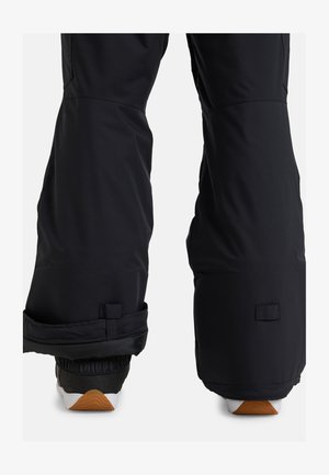 Black snow pants with a padded lower section, adjustable cuffs, and a sleek, matte finish; suitable for winter sports.