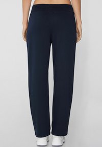 Marineblauwe joggers met een brede tailleband, gemaakt van zachte stof, met een ontspannen pasvorm en iets uitlopende broekspijpen.