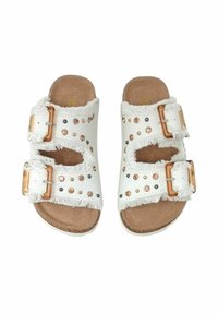 Bele sandale z dvema zaponkama, resicami in žebljički v različnih barvah, postavljene na rjavi, teksturirani podplati.