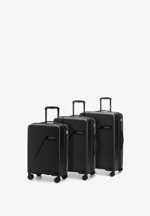 Three black suitcases made of textured hard-shell material. Each has a retractable handle and four wheels for mobility. Notable angled patterns.