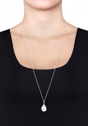 Collier en argent avec un pendentif en forme de goutte facettée, suspendu à une chaîne délicate. Le pendentif a une finition lustrée et des motifs complexes.