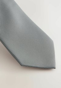 Grau gestreifter Krawatte mit einem strukturierten Muster, das kleine miteinander verbundene Formen zeigt. Schlankes Design, aus gewebtem Stoff gefertigt, verjüngt sich zu einer spitzen Spitze.