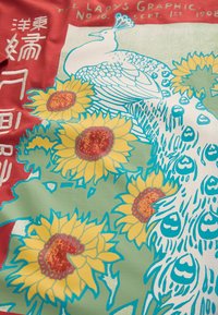 Valge paabulind peente suledega erksate kollaste päevalillede seas punasel ja rohelisel taustal, kus on Aasia märgid ja ingliskeelne tekst.