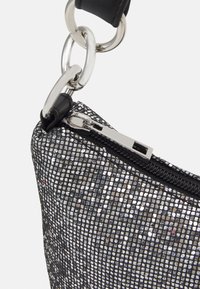 Borsa a rete nera con accenti metallici argento, dotata di chiusura con zip, forma elegante e tracolla a catena rimovibile. Vista ravvicinata.