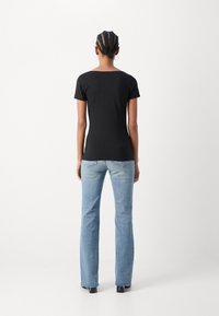 Black short-sleeve top with a rounded neckline, paired with light blue flared jeans, displaying a smooth texture and minimal visible detailing.