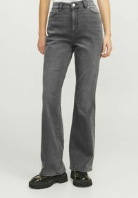 Jeans in denim grigi con vita alta e gamba dritta, dotati di chiusura con bottone e zip, tasche frontali e dettagli di cucitura a vista.