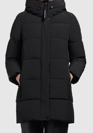 Sort quiltet dunjakke med hætte, lynlås foran og trykknapper, modellens hænder i sidelommer med lynlås, knælængde design.