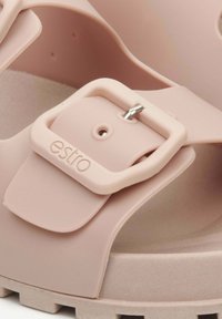 Sandale en caoutchouc rose avec un design moulé, une boucle réglable et une sangle texturée. La semelle présente un motif rayé pour une meilleure adhérence.