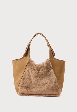Beżowa torebka z przodu pokryta sztucznym futrem i zamszowymi bokami, charakteryzująca się gładkim wykończeniem i dwiema solidnymi rączkami do noszenia.