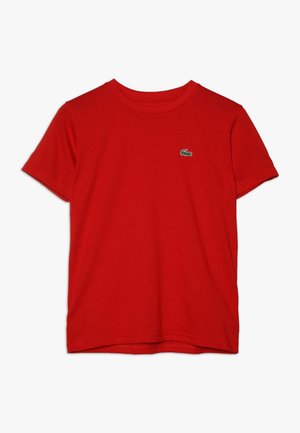 Czerwony bawełniany T-shirt z krótkimi rękawami, okrągłym dekoltem i małym zielonym logo krokodyla po lewej stronie klatki piersiowej. Gładka tekstura, casualowy design.