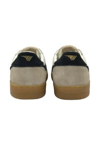 Herrskor med en beige mockakropp, svart mockahäl och vit textilövre. Har en sula av gummigummi och guldaccent på hälen.