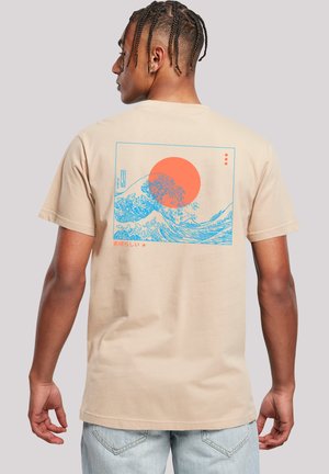 Beige Baumwoll-T-Shirt mit einem blauen Wellenmotiv und einer orangefarbenen Sonne auf dem Rücken. Kurze Ärmel, Rundhalsausschnitt und entspannter Schnitt.