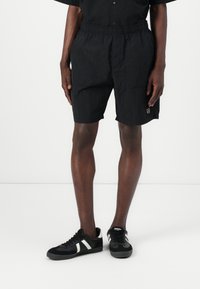 Sorte, lette shorts med elastisk talje og sidelommer, prydet med en diskret logo detalje på kanten. Båret med sorte sneakers.